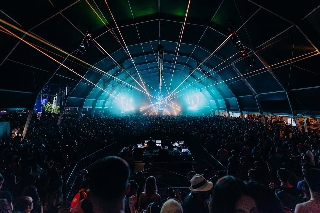 Carpa con luces turquesa y público al fondo