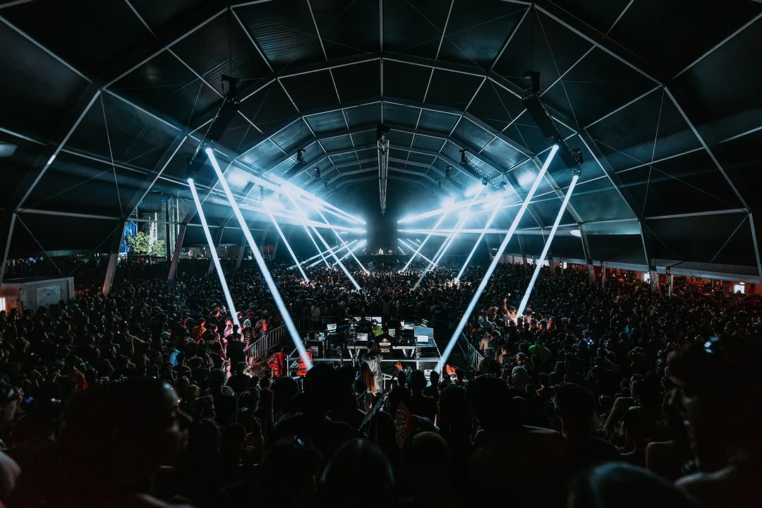 Haces de luz blancos cruzando la carpa sobre la pista llena