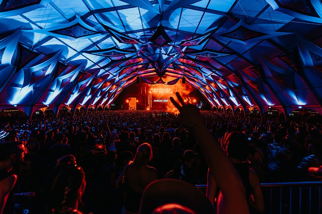 Interior de la carpa con techo de telas azules y escenario naranja al fondo