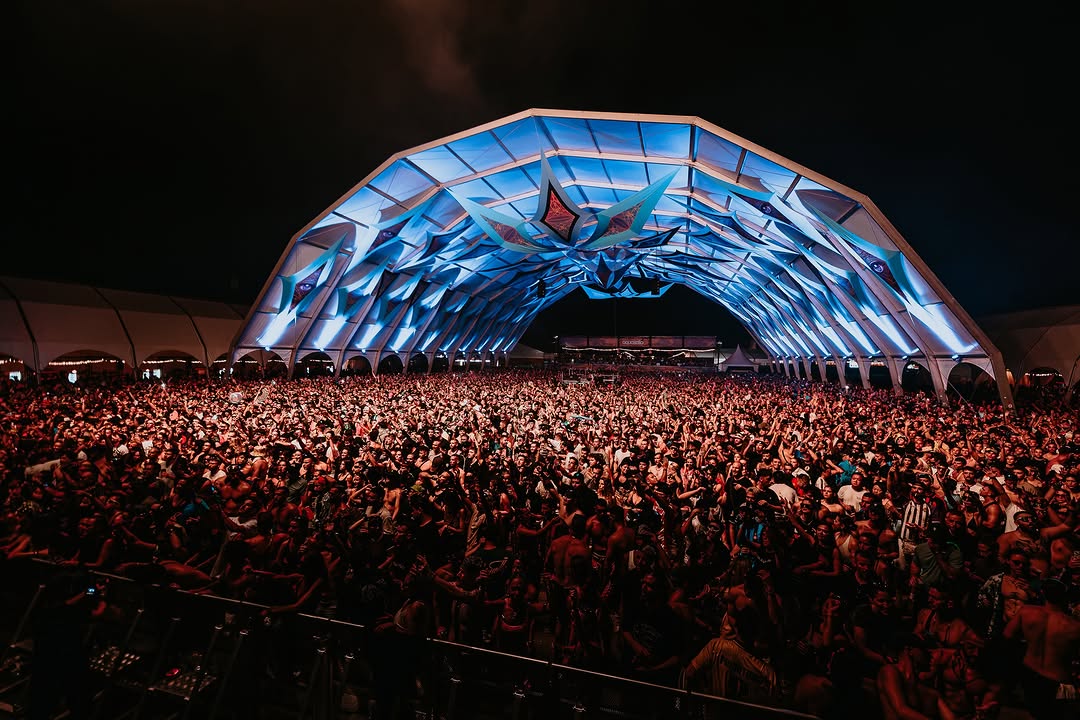 Vista frontal de la carpa iluminada en azul con miles de personas