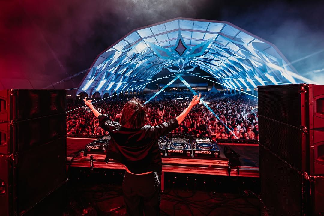DJ de espaldas con los brazos en alto ante la carpa azul de Aquasella